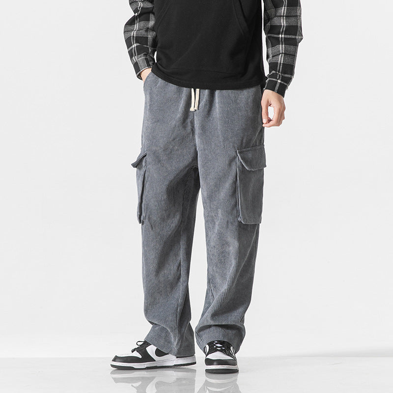 Uomo con pantaloni cargo grigi in velluto a coste, camicia a quadri e sneakers bianche e nere. Moda casual maschile, abbigliamento autunnale.
