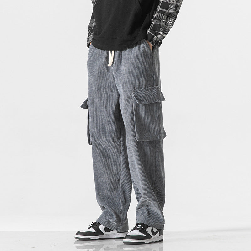 Pantaloni cargo grigi in velluto a coste, tasche laterali, indossati con sneakers bianche e nere, moda casual uomo, stile urbano moderno.