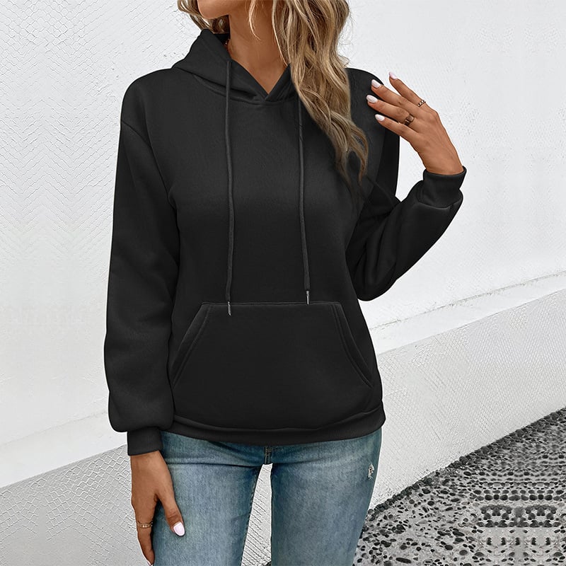 Donna con felpa nera con cappuccio e jeans, posa casual. Moda autunnale, abbigliamento comodo, stile urbano. Sfondo bianco minimalista.