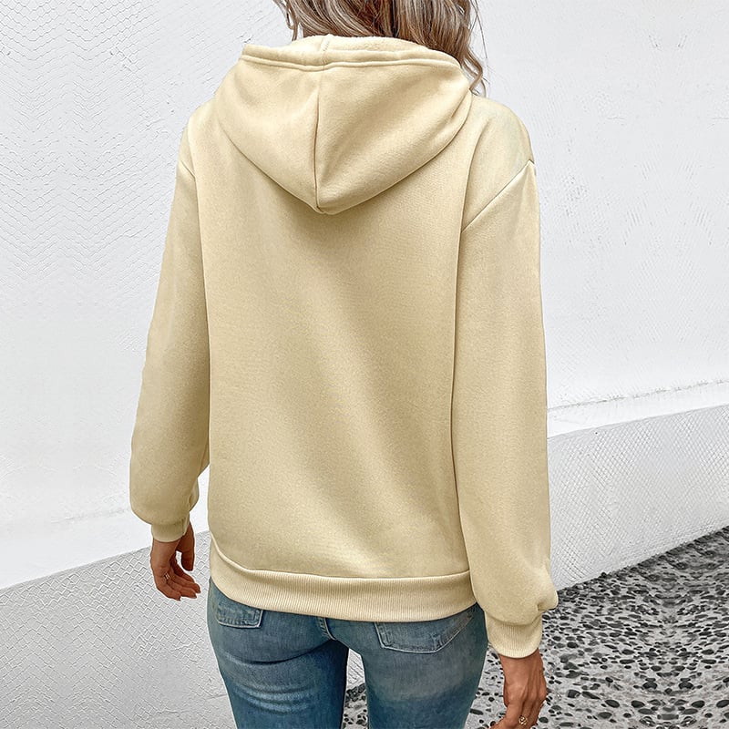 Donna con felpa beige con cappuccio vista posteriore, jeans blu, sfondo bianco. Moda casual, abbigliamento autunnale, stile urbano.