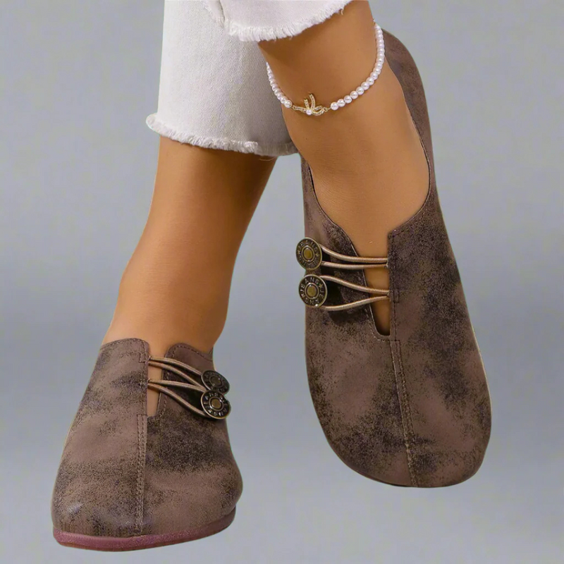 Scarpe da donna in pelle marrone con chiusura a bottoni decorativi, indossate con jeans bianchi e cavigliera di perle. Moda calzature eleganti.