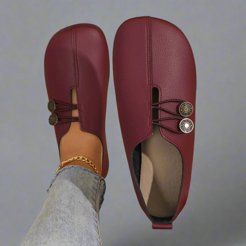 Scarpe mocassini donna in pelle rossa, design minimalista con bottoni decorativi, indossate con jeans. Calzature eleganti e comode per ogni occasione.