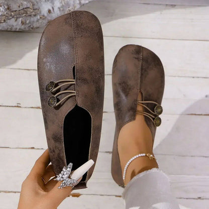 Scarpe da donna marroni in pelle vintage, con chiusura a bottoni e lacci decorativi. Design elegante e comodo, perfetto per look casual e chic.