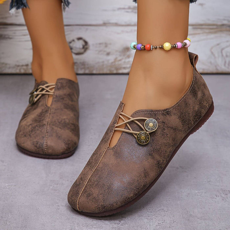 Scarpe casual marroni in pelle con lacci decorativi e cavigliera colorata su pavimento grigio. Moda donna, calzature eleganti e comode.