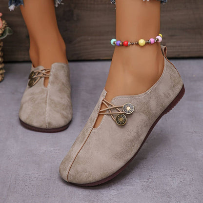 Scarpe da donna beige in pelle scamosciata con lacci decorativi e bottoni, indossate con cavigliera colorata. Design casual e moderno.