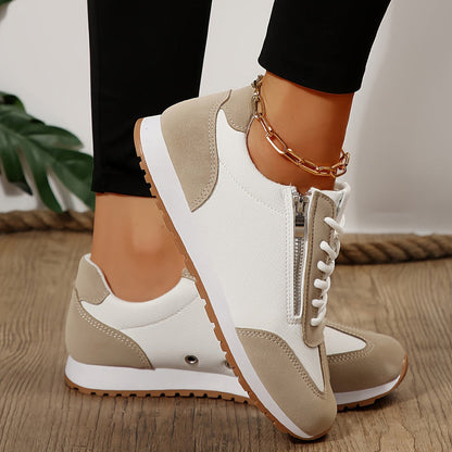 Scarpe da ginnastica bianche e beige con cerniera, suola in gomma antiscivolo, indossate su pavimento in legno. Accessorio cavigliera dorata.