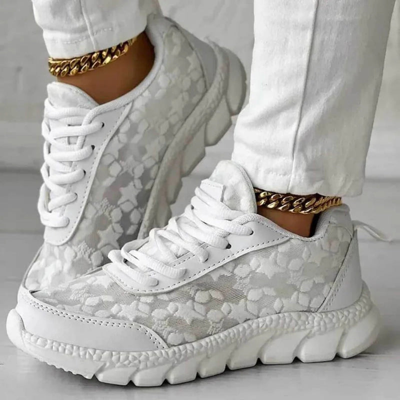 Scarpe da ginnastica bianche con motivo floreale, suola spessa e dettagli dorati. Moda casual, calzature trendy, stile moderno.