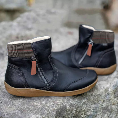 Stivaletti neri in pelle con cerniera laterale, suola marrone e fodera interna calda, posizionati su sfondo roccioso. Scarpe invernali eleganti e comode.
