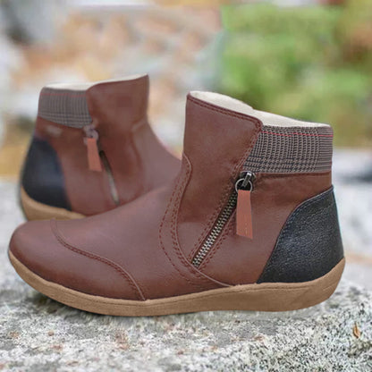 Stivaletti in pelle marrone con cerniera laterale, suola in gomma beige, dettagli neri sul tallone, su sfondo naturale. Scarpe autunnali eleganti.