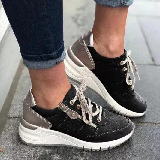 Scarpe da ginnastica nere e argento con lacci bianchi su pavimento grigio. Design moderno, suola spessa, perfette per moda casual e comfort.