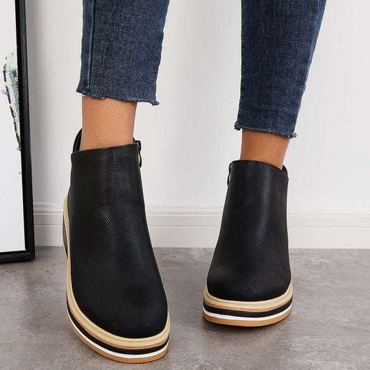 Stivaletti neri in pelle con suola spessa a strati, indossati con jeans aderenti. Scarpe moda donna, calzature autunnali eleganti e casual.
