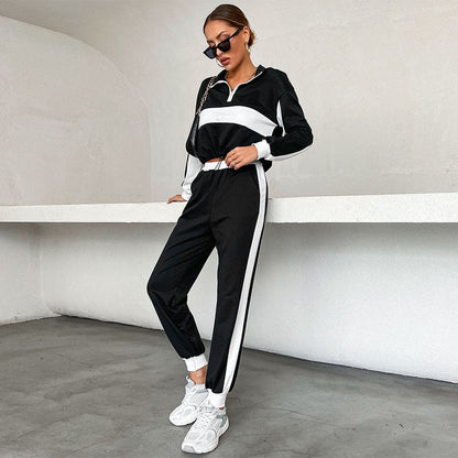 Donna in tuta sportiva bianca e nera, occhiali da sole, scarpe da ginnastica bianche, posa moderna. Abbigliamento casual, moda urbana.