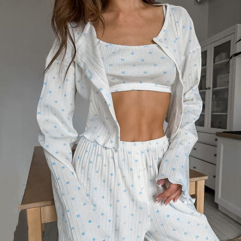 Donna in pigiama bianco a pois blu, top corto e pantaloni coordinati, in cucina moderna. Moda loungewear, abbigliamento comodo per casa.