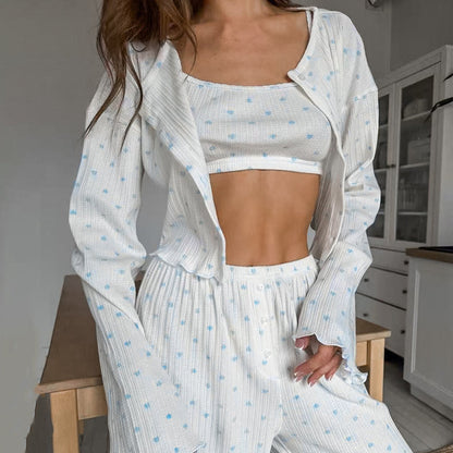 Donna in pigiama bianco a pois blu, top corto e pantaloni coordinati, in cucina moderna. Moda loungewear, abbigliamento comodo per casa.