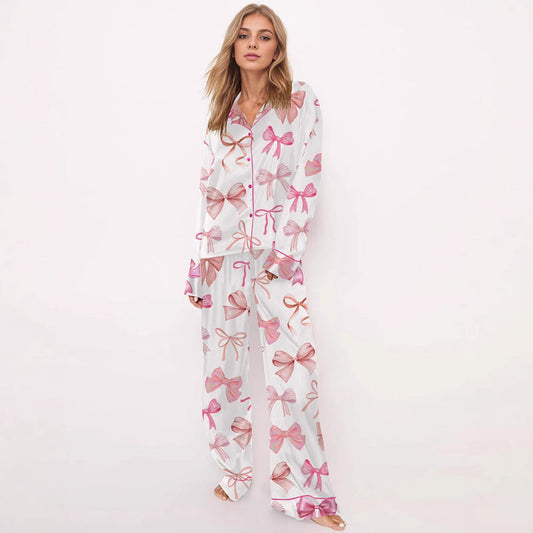 Donna in pigiama bianco con fiocchi rosa, maniche lunghe e pantaloni coordinati. Moda notte elegante, abbigliamento comodo per casa.