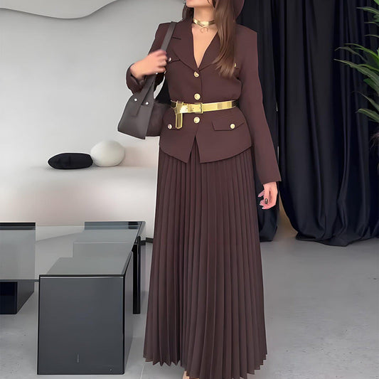 Donna in abito marrone elegante con cintura dorata, borsa nera, in un salotto moderno. Moda autunnale, stile sofisticato, tendenze 2023.