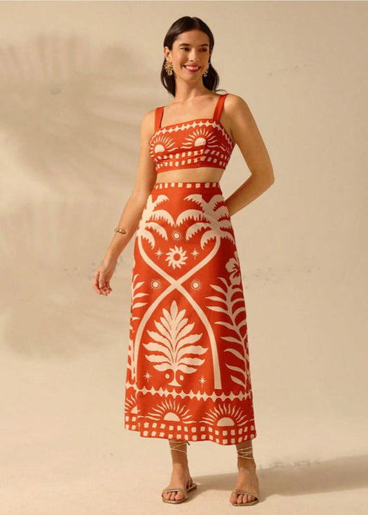 Donna in abito lungo rosso con motivi bianchi floreali, sandali beige, sfondo neutro. Moda estiva elegante, abbigliamento femminile trendy.