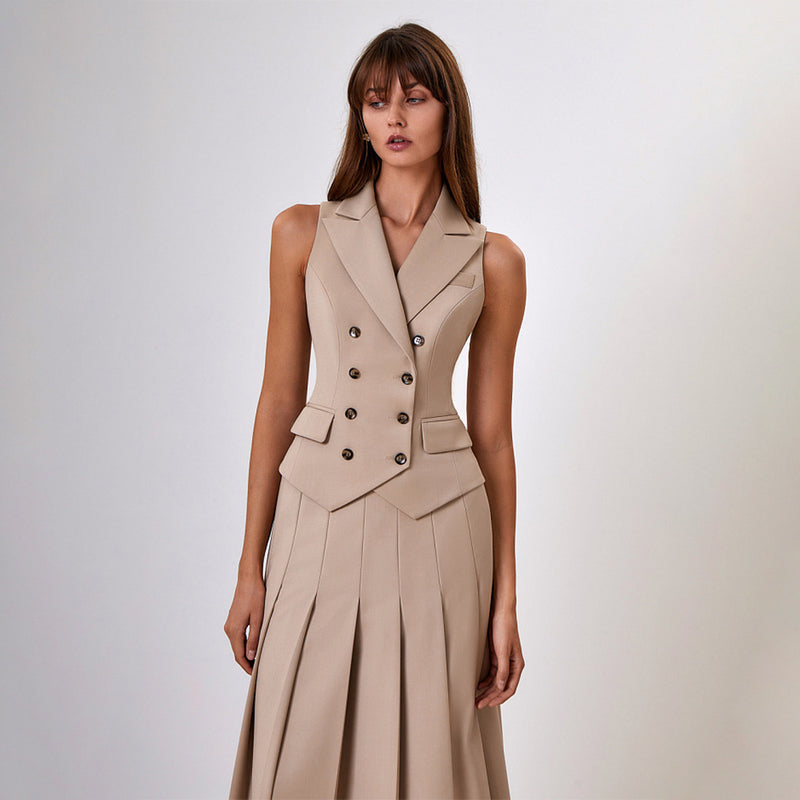 Donna in abito beige elegante senza maniche, con bottoni doppiopetto e gonna a pieghe. Moda femminile, stile sofisticato, abbigliamento formale.
