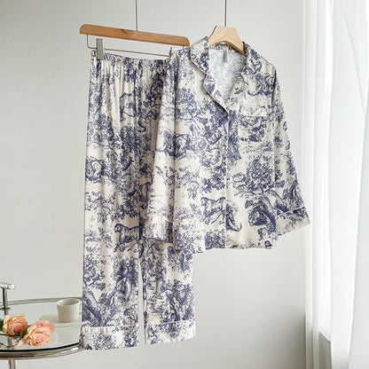 Pigiama donna in raso bianco con stampa blu a motivi floreali e animali, appeso su grucce. Elegante e confortevole, ideale per la notte.