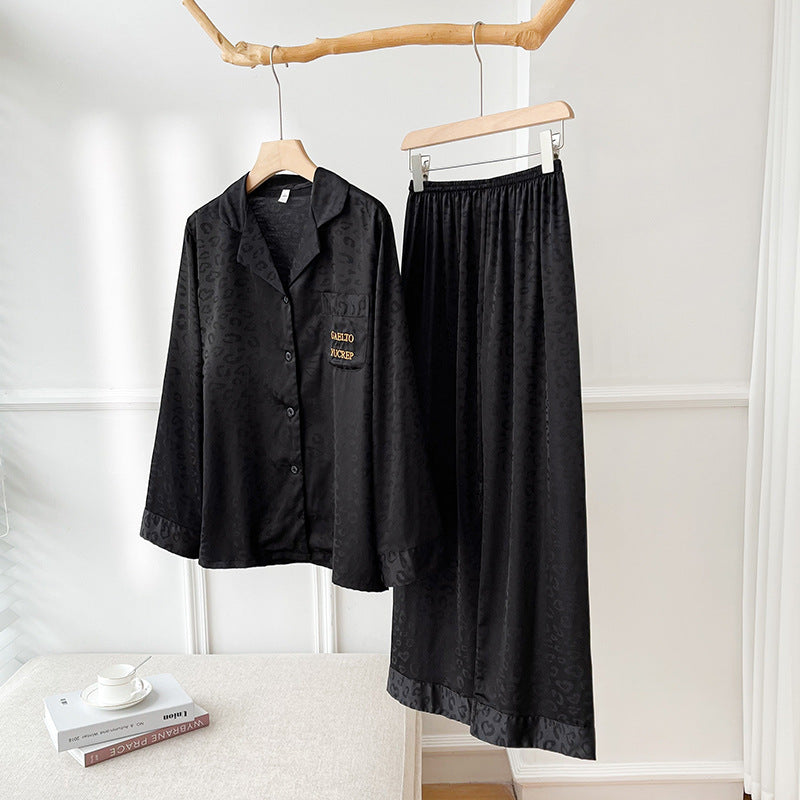 Pigiama donna nero in raso, camicia a maniche lunghe con bottoni e pantaloni lunghi. Elegante set da notte, tessuto lucido, stile leopardato.