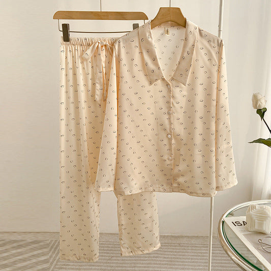 Pigiama donna in seta beige con motivo a luna, camicia a maniche lunghe e pantaloni con elastico in vita, appeso su gruccia in camera luminosa.