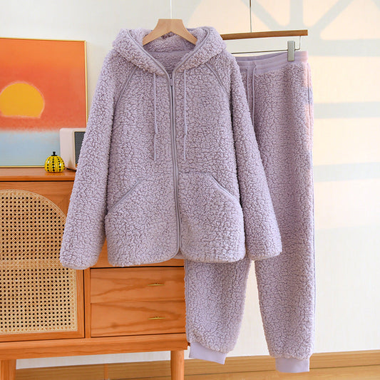 Tuta in pile viola chiaro con cappuccio e pantaloni, appesa su gruccia in una stanza luminosa. Abbigliamento invernale caldo e confortevole.