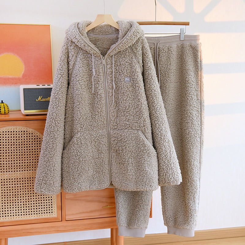 Set pigiama in pile beige, composto da felpa con cappuccio e pantaloni, appeso su gruccia in una stanza luminosa. Abbigliamento comodo e caldo.