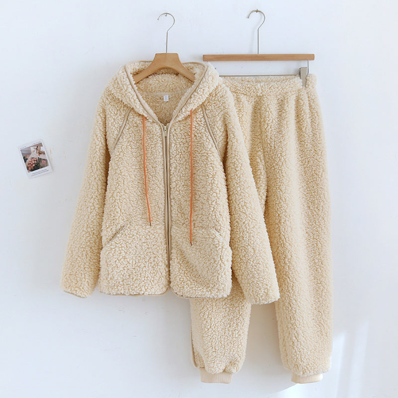 Set coordinato in pile beige, composto da felpa con cappuccio e pantaloni, appeso a grucce su sfondo bianco. Abbigliamento invernale caldo e morbido.