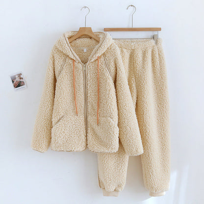 Set coordinato in pile beige, composto da felpa con cappuccio e pantaloni, appeso a grucce su sfondo bianco. Abbigliamento invernale caldo e morbido.