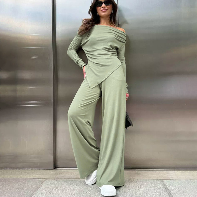 Donna con tuta verde oliva elegante, spalle scoperte, pantaloni larghi, scarpe bianche, posa moderna. Moda femminile, abbigliamento casual chic.