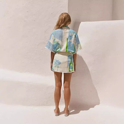 Donna in abito estivo colorato, con motivi geometrici, in piedi contro un muro bianco. Moda estiva, abbigliamento leggero, stile casual.