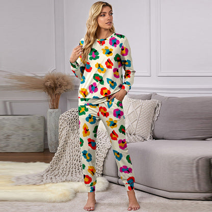 Donna in pigiama colorato floreale, seduta su divano grigio in salotto moderno. Arredamento elegante con tappeto morbido e piante decorative.