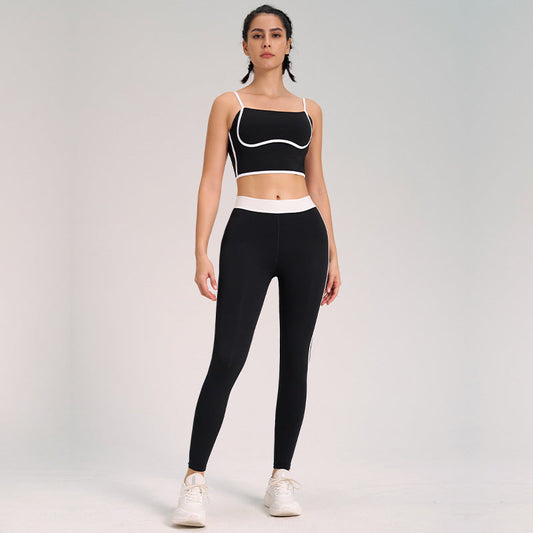 Donna in abbigliamento sportivo nero e bianco, top e leggings, posa su sfondo neutro. Moda fitness, abbigliamento palestra, stile attivo.