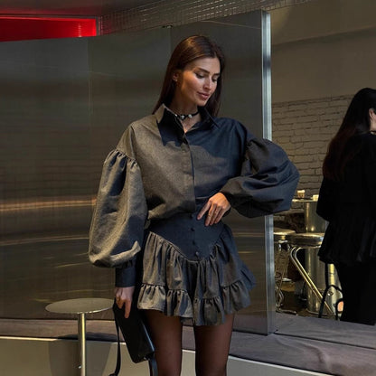 Donna con camicia a maniche a sbuffo e gonna a balze grigia in un ambiente moderno. Moda autunnale elegante, outfit sofisticato, stile urbano.