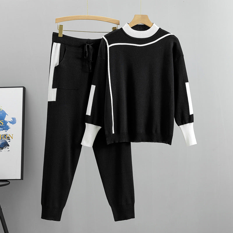 Completo sportivo nero e bianco da donna, composto da maglione a maniche lunghe e pantaloni con tasche, appeso su gruccia. Moda casual elegante.