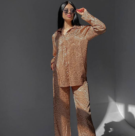 Donna con occhiali da sole indossa pigiama leopardato marrone, posa con mano in tasca. Moda femminile, abbigliamento casual elegante.