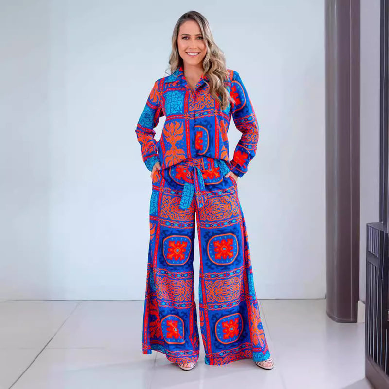 Donna sorridente in tuta colorata blu e rossa con motivi geometrici, posa in un ambiente moderno. Moda femminile, abbigliamento vivace, stile casual.