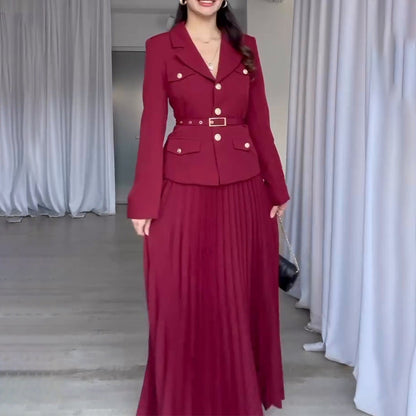Donna in abito lungo rosso elegante con giacca abbinata, posa in interni moderni. Moda femminile, abbigliamento formale, stile sofisticato.