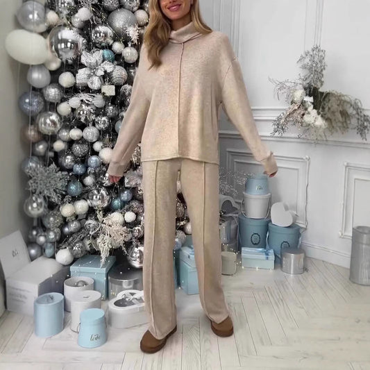 Donna in abbigliamento beige davanti a un albero di Natale decorato con palline argentate e bianche, circondata da scatole regalo eleganti.