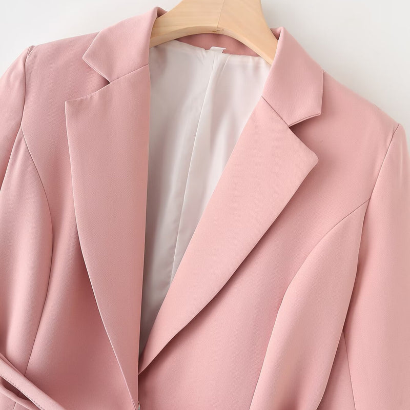 Giacca blazer rosa chiaro su appendiabiti in legno, tessuto elegante e moderno, ideale per moda donna, abbigliamento formale e casual chic.
