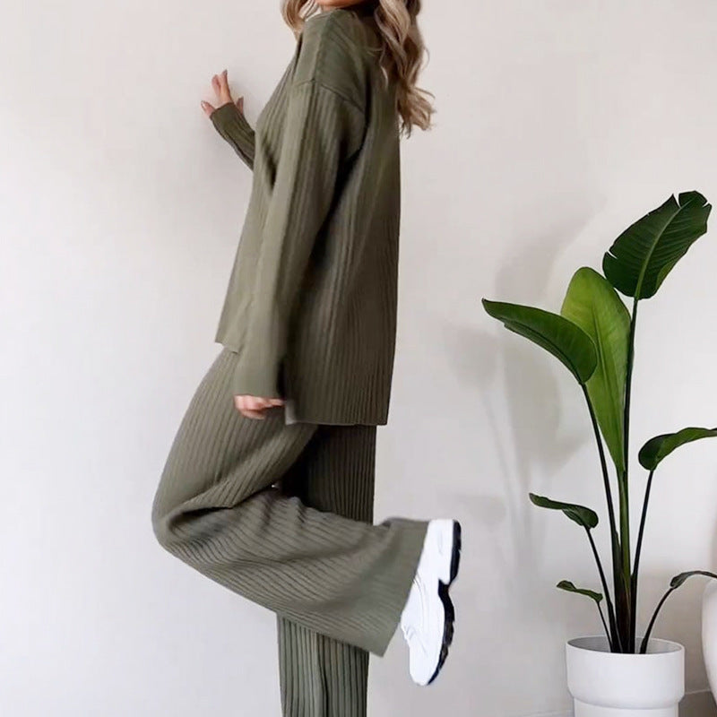 Donna in completo verde oliva a coste, posa accanto a pianta d'appartamento. Moda autunnale, abbigliamento casual, stile confortevole.