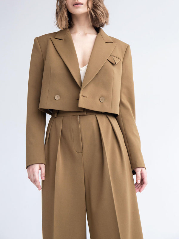 Donna in abito marrone elegante, giacca corta e pantaloni a vita alta. Moda contemporanea, abbigliamento femminile chic, stile sofisticato.