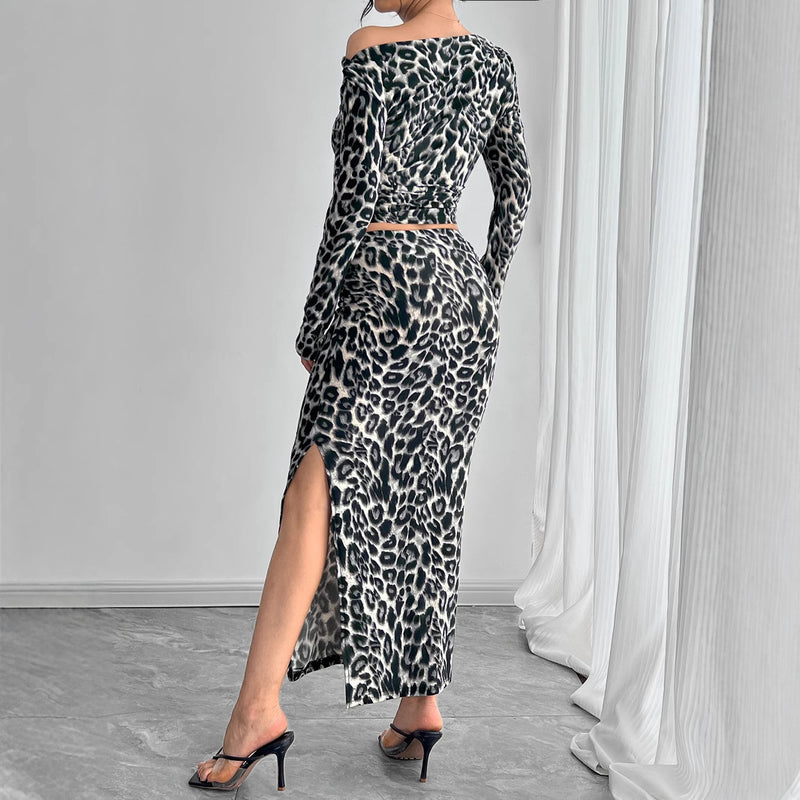 Abito lungo leopardato con spacco laterale, maniche lunghe, indossato con sandali neri con tacco. Stile elegante e moderno per occasioni speciali.
