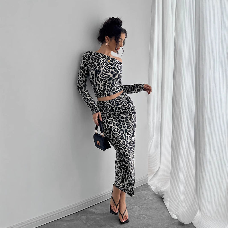 Donna in abito leopardato elegante, posa accanto a una tenda bianca. Indossa sandali neri e tiene una borsa nera. Moda femminile, stile moderno.