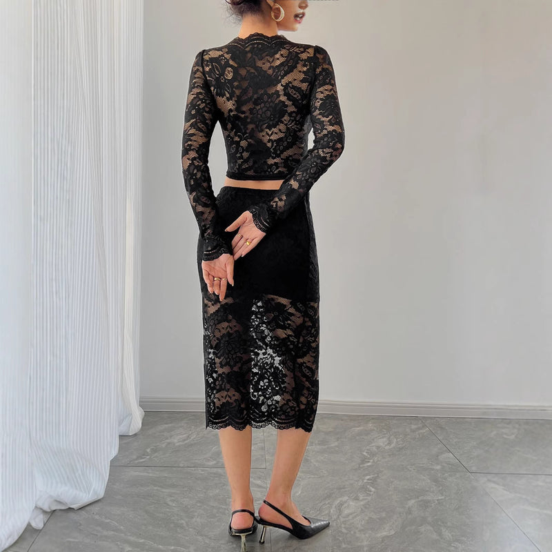 Donna in abito nero di pizzo trasparente, maniche lunghe, gonna midi, tacchi neri. Eleganza, moda femminile, abbigliamento da sera.