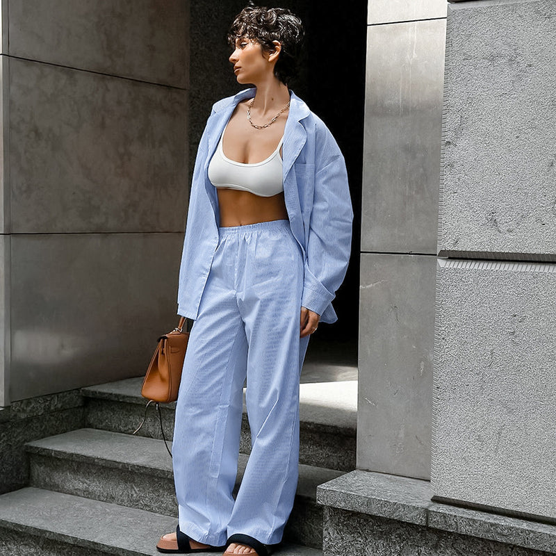 Donna con completo azzurro e top bianco su gradini di cemento. Moda urbana, abbigliamento casual, stile estivo.