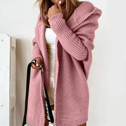 Donna con cardigan rosa in maglia, cappuccio, maniche lunghe, indossa top bianco e pantaloncini. Moda autunnale, abbigliamento casual elegante.