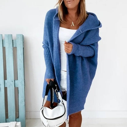 Donna con cardigan blu oversize, top bianco e borsa a tracolla bianca. Moda casual autunnale, abbigliamento femminile trendy.