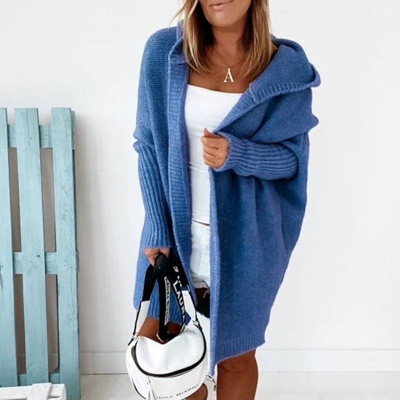 Donna con cardigan blu oversize, top bianco e borsa a tracolla bianca. Moda casual autunnale, abbigliamento femminile trendy.