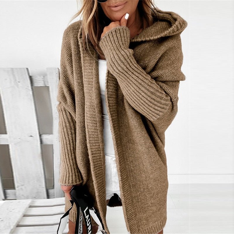 Donna con cardigan oversize marrone, cappuccio e maniche lunghe, su sfondo bianco. Moda autunnale, abbigliamento casual elegante.
